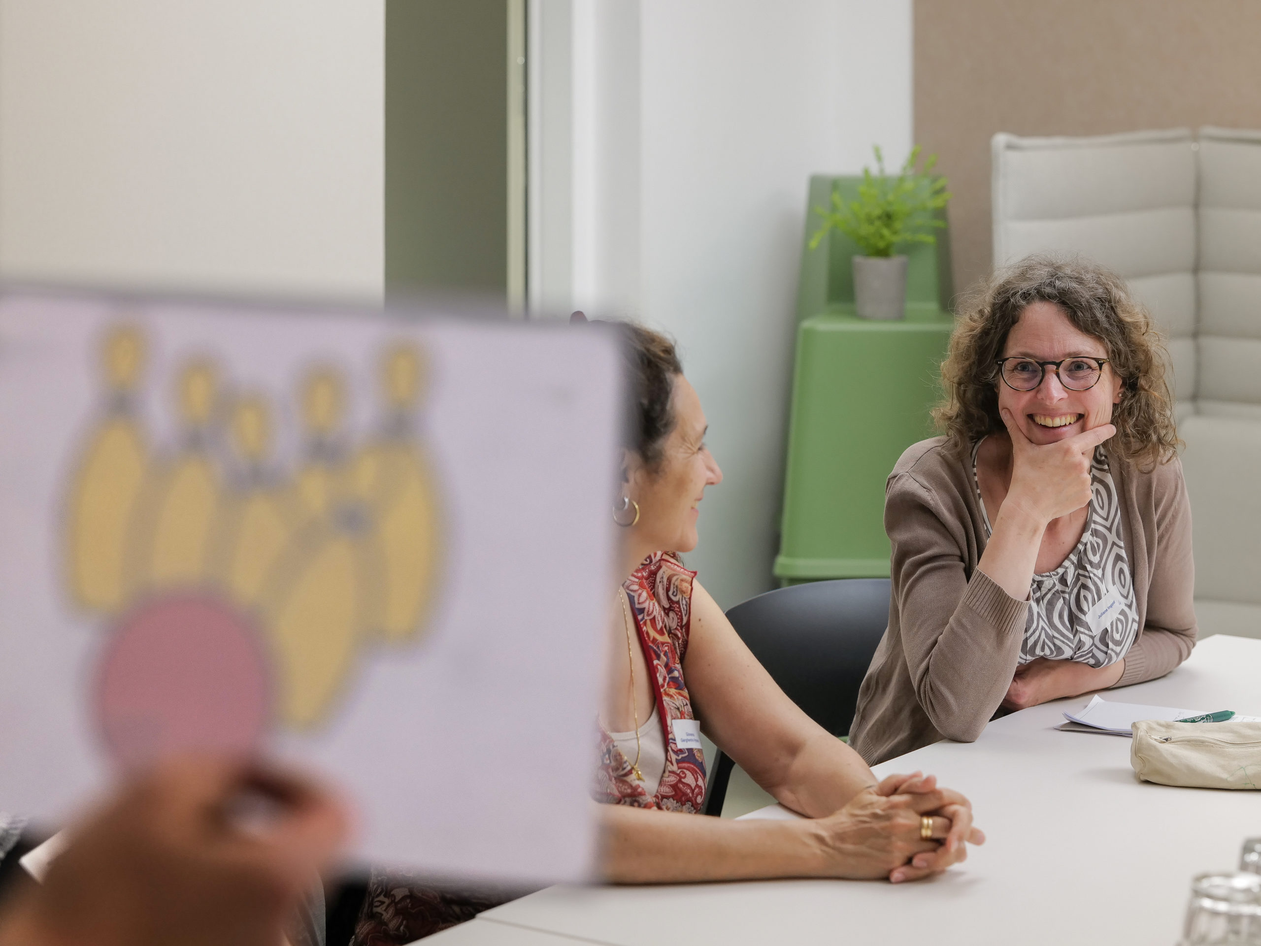 Una partecipante sorride mentre il facilitatore le presenta un pittogramma durante il workshop di ideazione.