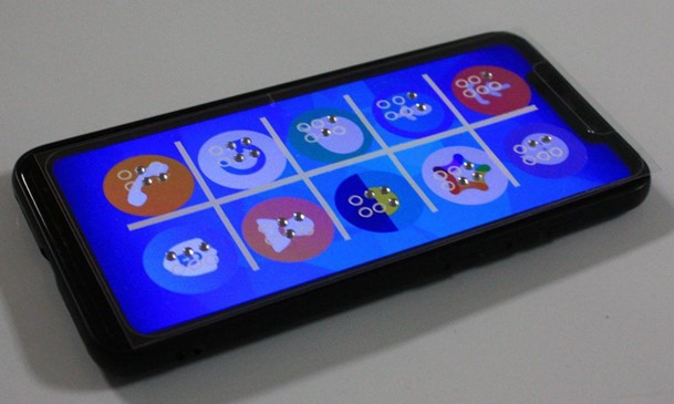 L'écran d'accueil d'un smartphone, avec 10 applications représentées par des pictogrammes. Par dessus l'écran, il y a une pellicule transparente en relief, avec une lettre en braille sur l'emplacement de chaque pictogramme.