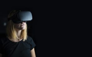 Une femme portant des lunettes de réalité virtuelle, sur un fond noir.